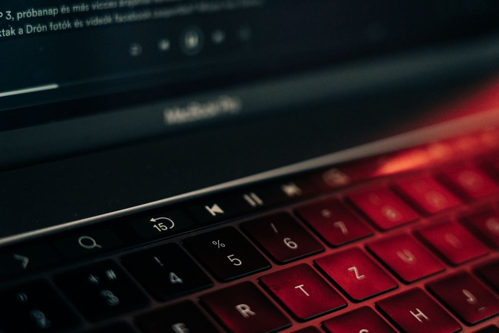 A vibrant close-up of a backlit laptop keyboard with a glowing red hue, showcasing modern technology.