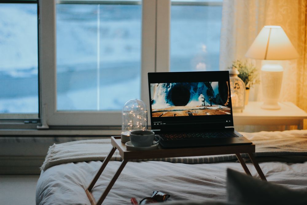 Relaxing bedroom scene with a laptop on a tray table, perfect for a cozy night in.