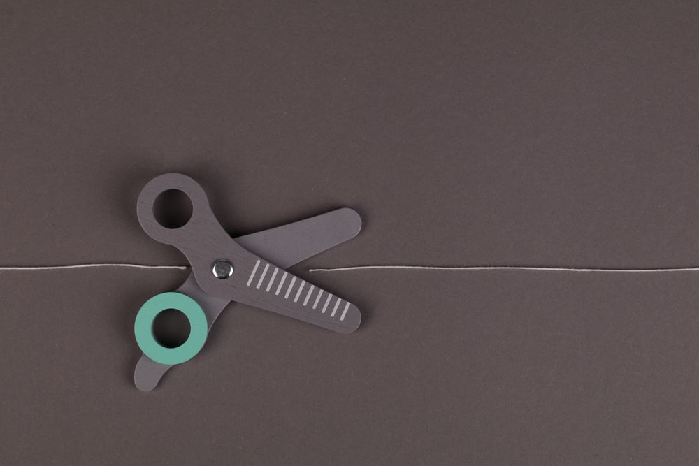 A minimalist flat lay of scissors on a gray background with a string, creating a modern composition.