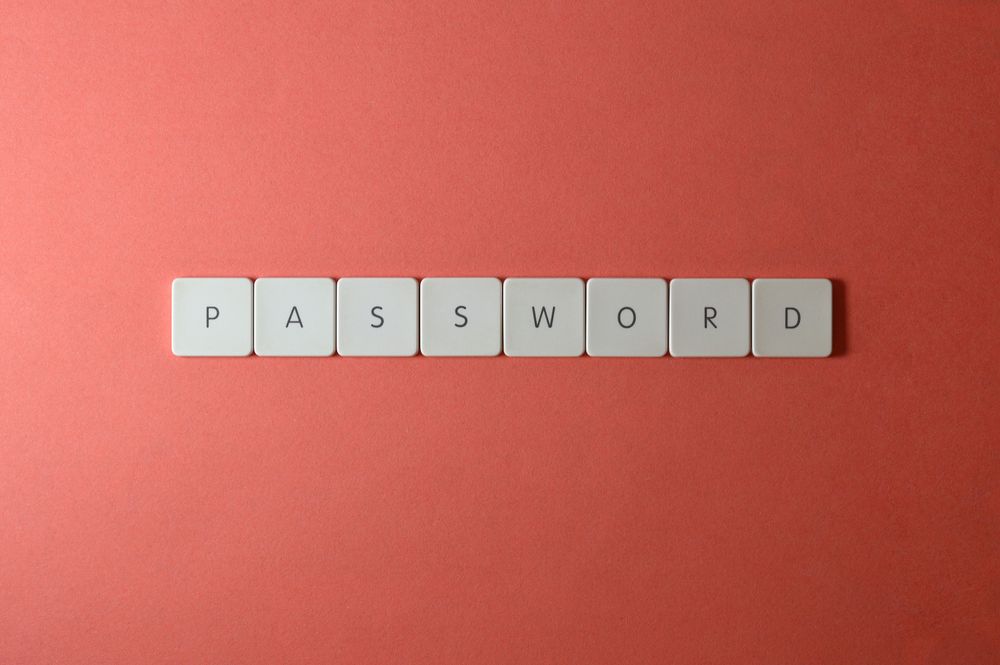 Focus on password security with white keyboard tiles spelling 'PASSWORD' on a coral background.