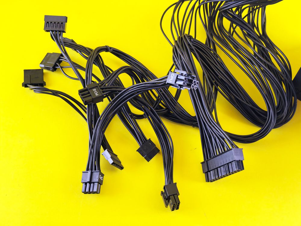 Black computer cables splayed on a vibrant yellow surface, highlighting technology connection themes.