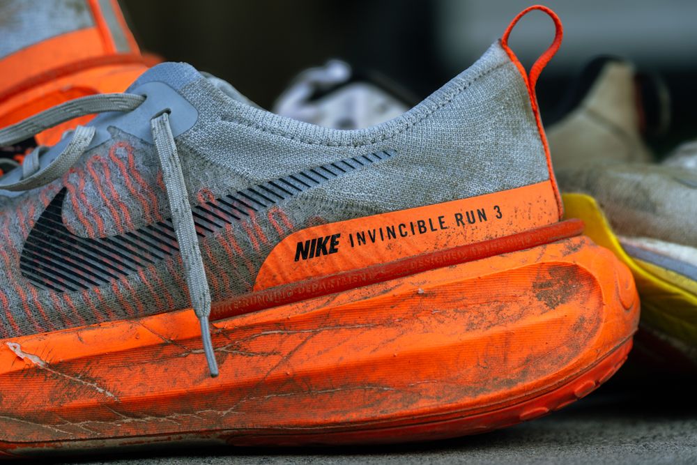 Close-up of worn Nike Invincible Run 3 shoes on concrete, showing wear and tear.