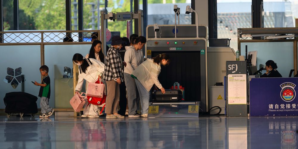 Travelers undergo security screening at an airport terminal.