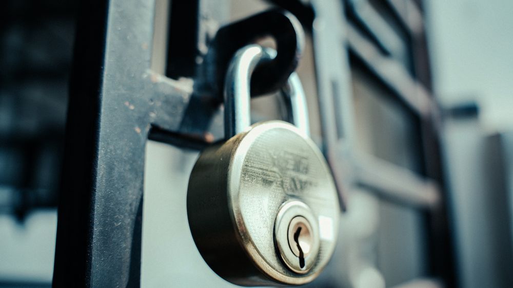 Steel padlock securely fastened on a gate, symbolizing security and protection.