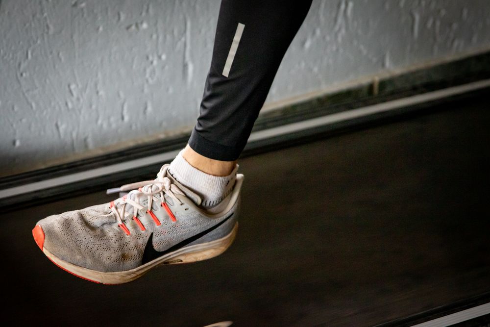 A detailed view of a sneaker mid-stride on a treadmill, showcasing active lifestyle footwear.