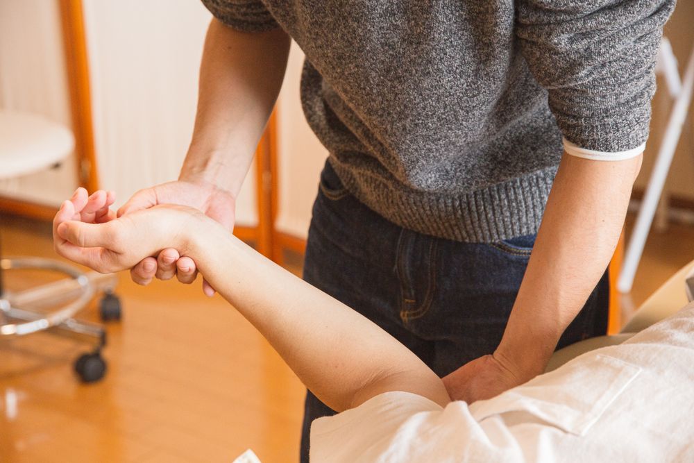 Crop anonymous osteopath massaging injured hand of client in process of treatment procedure