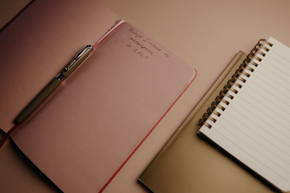 Top view of open planner and notebook with a pen, ideal for planning and writing.